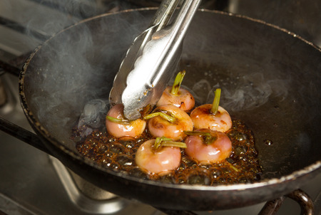 Fresh organic baby turnips, in a metal frying pan, being cooked and caramelised in a sauce.の写真素材