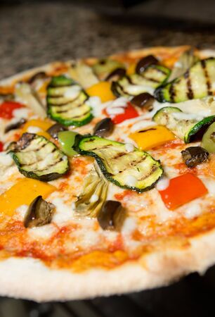 Close up of a Vegetarian thin crust  pizza, with grilled courgette, peppers, aubergine, artichoke, cheese and tomato toppingの写真素材