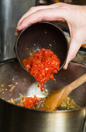 Freshly chopped organic vine ripened tomatoes, being dropped into a hot frying pan as part of a recipe stage.の写真素材