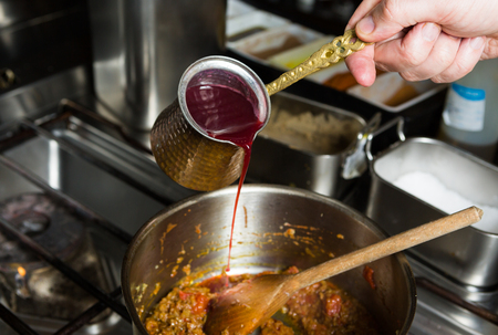 Sweet blended pomegranate sauce being poured into a hot frying pan of ingredients の写真素材