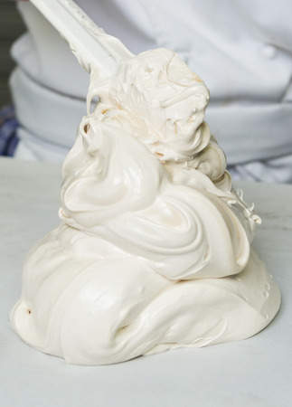 A beautiful rich and creamy , white whipped meringue mixture being scooped out onto a kitchen surface.の写真素材