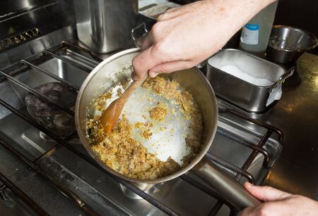 Turmeric powder being mixed into a pan of frying minced garlic and finely sliced onion. Step by step recipe cooking.の写真素材