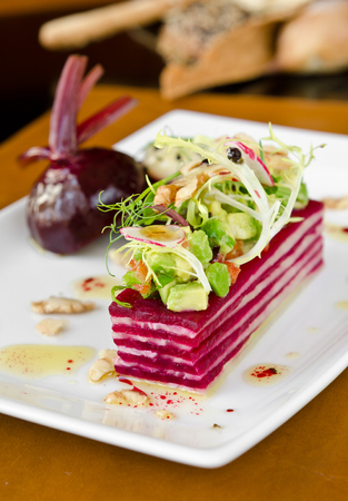A beautiful gourmet, organic sliced beetroot salad, served with avocado, tomato, onion, nuts, reddish, onion and olive oil. の写真素材