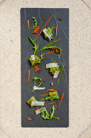 Rich green spinach polenta, served with sliced olives, rocket, chilli, sun dried tomato and thin parmesan slices. Served on a contemporary slate plate.の写真素材