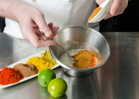fresh organic tandoori spice ingredient mix, being blended and mixed in a metal bowl in preparation for a marinade.の写真素材