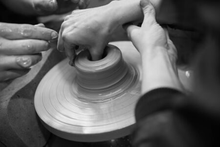 Hands working on a spinning pottery wheel, making pottery out of clay mud. close up photograph with a shallow depth of field.の写真素材