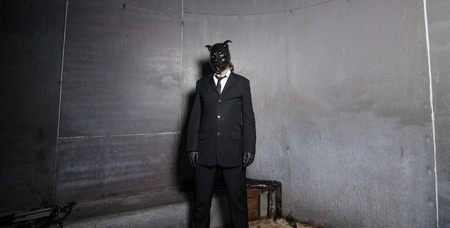 A corporate man in a dirty scruffy suit wearing a black pigs mask in a dark sinister background, photographed with moody cinematic lighting. evil dirty corporate pigs.の写真素材