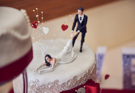 A beautiful sweet creamy Wedding cake with beautiful flowers and decorations, with 3d printed funny bride and groomshot with a shallow depth of field. Love words.の写真素材