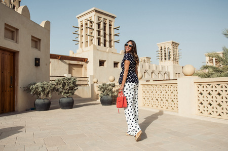 dubai, united arab emirates, 02/02/2017, A fashionable arabic woman wearing fashionable designer clothes, walking around traditional arabic wind catcher buildings.のeditorial素材