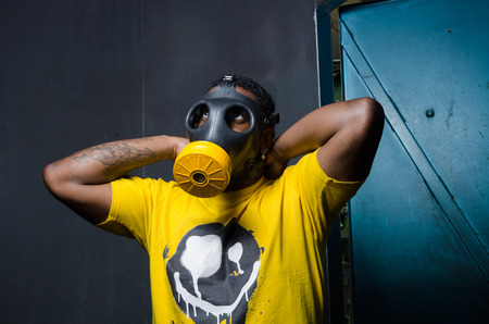 A scary man with reflection eyes in an industrial setting wearing a horror gas mask staring and...