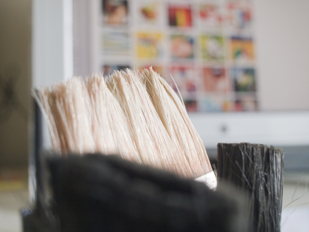 Old worn Rustic artistic artists paintbrushes, in a metal tin, with a keyboard in the background. Analogue and digital contrast.の写真素材