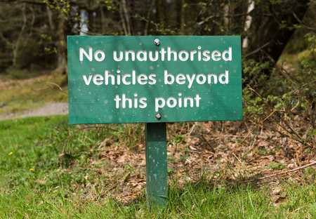 A no unauthorised vehicles beyond this point, hand carved wooden warning parking sign, on a stake with a countryside background.の写真素材