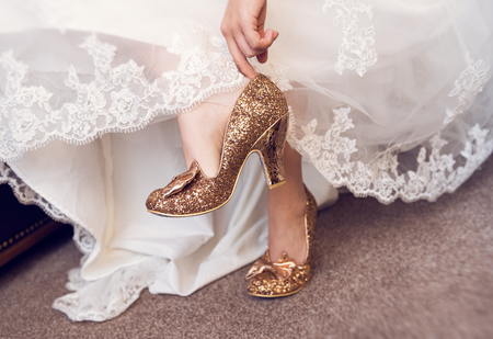 A bride putting on her wedding shoes in preparation for the wedding ceremony. Soft delicate white and cream colours. feet and shoes.の写真素材
