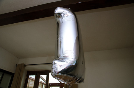 A large silver metallic chrome ballon in the shape of a number one number. Floating helium silver metal balloon.の写真素材