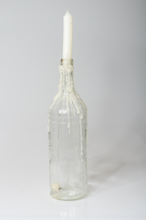 london, england, 05/05/2017, A clear glass bottle with melted dripping candle dripping down the bottle. The white clean candle is new and unlit.の写真素材