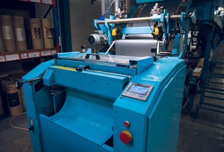 An  industrial wallpaper and paint factory with giant industrial wall paper rolling machines in...