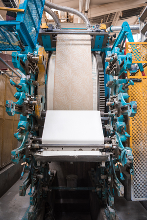An empty quiet industrial wallpaper and paint factory with giant industrial paint rolling machines,...