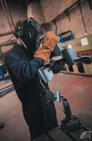 london, england, 02/02/2018 A vibrant action shot of a skilled working metal welder in action, welding metal. Photographed with a slow shutter speed and spark trails. Orange and teal.のeditorial素材
