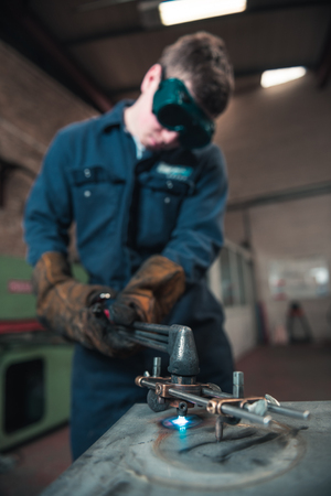 london, england, 02/02/2018 A vibrant action shot of a skilled working metal welder in action, welding metal. Photographed with a slow shutter speed and spark trails. Orange and teal.のeditorial素材