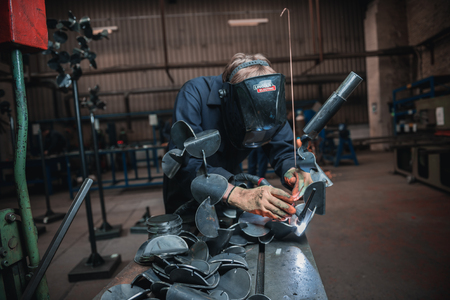 london, england, 02/02/2018 A vibrant action shot of a skilled working metal welder in action, welding metal. Photographed with a slow shutter speed and spark trails. Orange and teal.のeditorial素材
