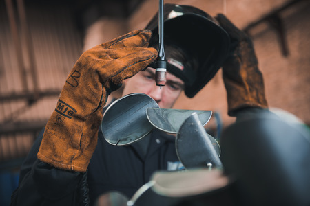 london, england, 02/02/2018 A vibrant action shot of a skilled working metal welder in action, welding metal. Photographed with a slow shutter speed and spark trails. Orange and teal.のeditorial素材