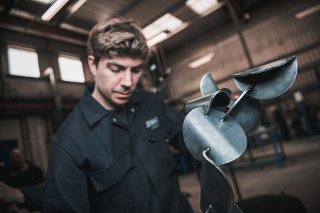 london, england, 02/02/2018, Young industrial metal working apprentice worker learning various metal working skills in an industrial factory setting. Apprentice schemes returning to england.のeditorial素材