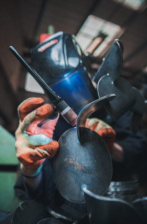 london, england, 02/02/2018 A vibrant action shot of a skilled working metal welder in action, welding metal. Photographed with a slow shutter speed and spark trails. Orange and teal.の写真素材