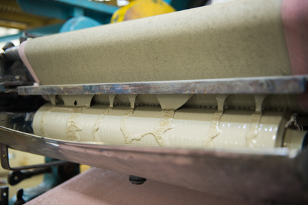 An industrial wallpaper and paint factory with giant industrial wall paper rolling machines, photographed close up,  in various colours. green paint being mixed.の写真素材