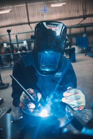 london, england, 02/02/2018 A vibrant action shot of a skilled working metal welder in action, welding metal. Photographed with a slow shutter speed and spark trails. Orange and teal.のeditorial素材