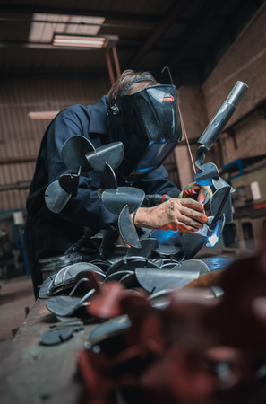london, england, 02/02/2018 A vibrant action shot of a skilled working metal welder in action, welding metal. Photographed with a slow shutter speed and spark trails. Orange and teal.のeditorial素材