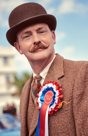 london, England, 05/05/2017, A stylish retro vintage fashionable gentleman in a brown blazer, rosette, hipster moustache and a bowler hat at a vintage event at the midland hotel.のeditorial素材