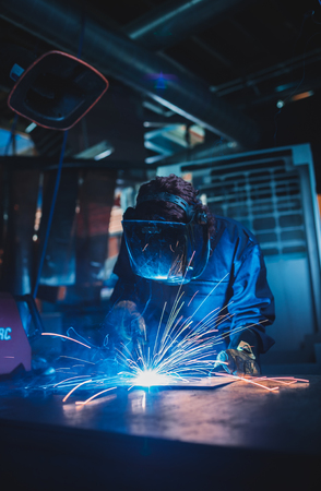 london, england, 02/02/2018 A vibrant action shot of a skilled working metal welder in action, welding metal. Photographed with a slow shutter speed and spark trails. Orange and teal.のeditorial素材