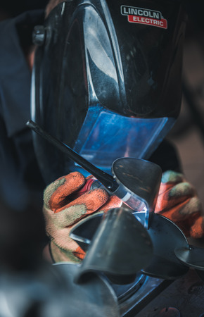 london, england, 02/02/2018 A vibrant action shot of a skilled working metal welder in action, welding metal. Photographed with a slow shutter speed and spark trails. Orange and teal.のeditorial素材