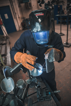london, england, 02/02/2018 A vibrant action shot of a skilled working metal welder in action, welding metal. Photographed with a slow shutter speed and spark trails. Orange and teal.のeditorial素材