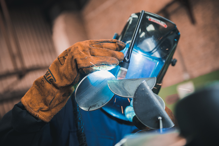london, england, 02/02/2018 A vibrant action shot of a skilled working metal welder in action, welding metal. Photographed with a slow shutter speed and spark trails. Orange and teal.のeditorial素材