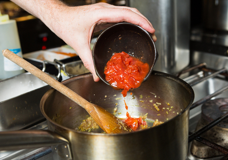 Freshly chopped organic vine ripened tomatoes, being dropped into a hot frying pan as part of a recipe stage.の写真素材