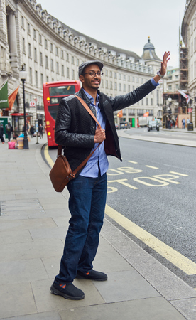 05/05/2017 A young arabic male tourist in london hailing a taxi cab on the world famous high streets. Urban cosmopolitan city living.のeditorial素材
