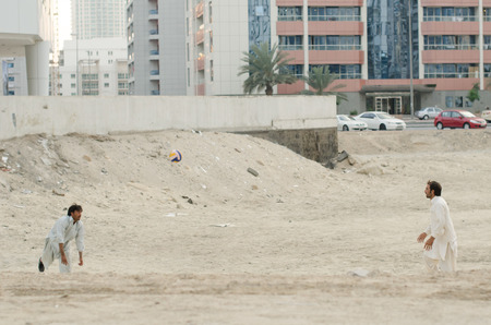 15/05/2017 Tecom, Dubai, Pakistani immigrant workers workforce relaxing and taking time to play some volleyball on the dusty construction site grounds. Dubai workers fining time to play sport.のeditorial素材