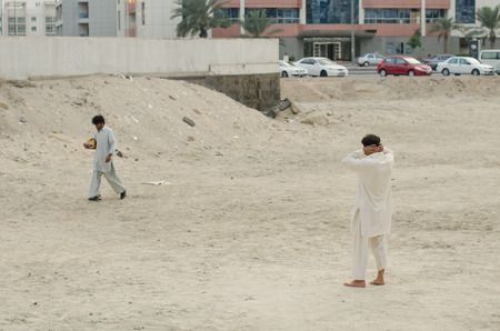 15/05/2017 Tecom, Dubai, Pakistani immigrant workers workforce relaxing and taking time to play some volleyball on the dusty construction site grounds. Dubai workers fining time to play sport.のeditorial素材