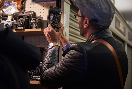 05/05/2017 A young arabic male tourist in london on the world famous carnaby street, looking and trying out retro film and movie cameras in an antique camera shop.のeditorial素材