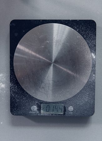 A used digital weighing scale shot from above in a grey and silver kitchen. perfect for weighing food for recipe and baking. backgrounds and textures.の写真素材