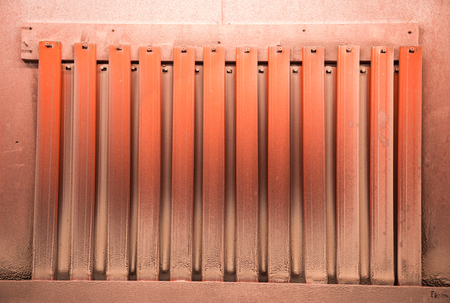 A dirty spray paint booth in an art studio, a place to spray paint onto objects in a controlled safe and clean environment. Neon orange  with daylight bulb lighting.の写真素材
