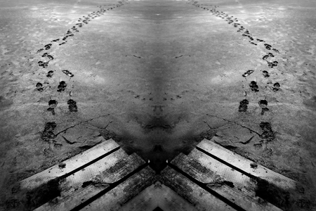 A creative Black and white grunge footprint trail in a dirty grunge sand beach sediment. one way footprints, in a moody creative setting. の写真素材