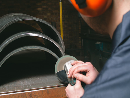 A man working with a grinder in a factory, creating sparks. metal working apparent angle grinding metal and steel parts. matte dark photography.の写真素材