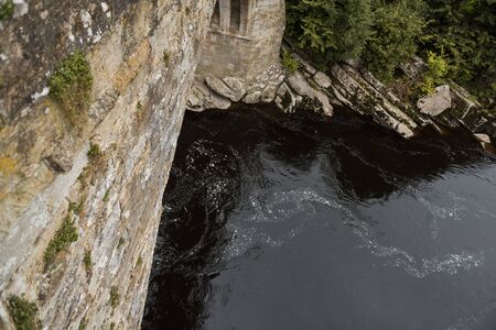 A viewpoint looking down off the side of a stone bridge. a place where people thinking of suicide may jump. cold dark water looms below. mental health problems.の写真素材