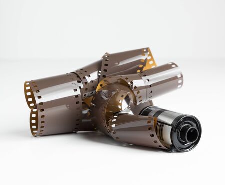 A roll of messy used vintage retro 35mm camera film isolated on a white background. Old expired processed camera film stock. ruined and damaged camera film. light exposure.の写真素材