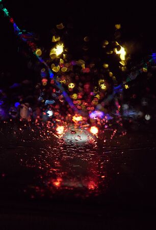 Abstract painterly rain drops on a car window with vibrant city and street lights out of focus in the background. Tired and drunk driving in wet and rainy conditions. safe driving.の写真素材