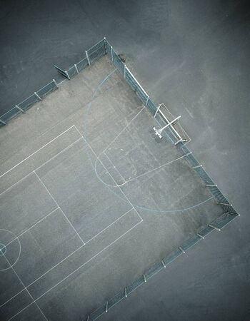 An empty gritty cold urban inner city basketball court, photographed from above. drone photography showing court lines, tennis court and a concrete basketball court. atmospheric overhead viewpoint.の写真素材