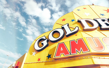 A bright yellow vintage gambling arcade sign on the seafront in the seaside town of blackpool england, against a vivid blue sky. Golden yellows and red. happy memories from childhood.のeditorial素材
