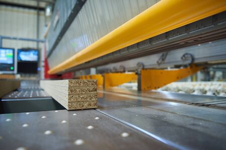 Industrial automated robot wood cutting machinery cutting wooden chip board flat pack furniture in a factory. joinery and carpentry machine cutting to precision. automated factory work.の写真素材